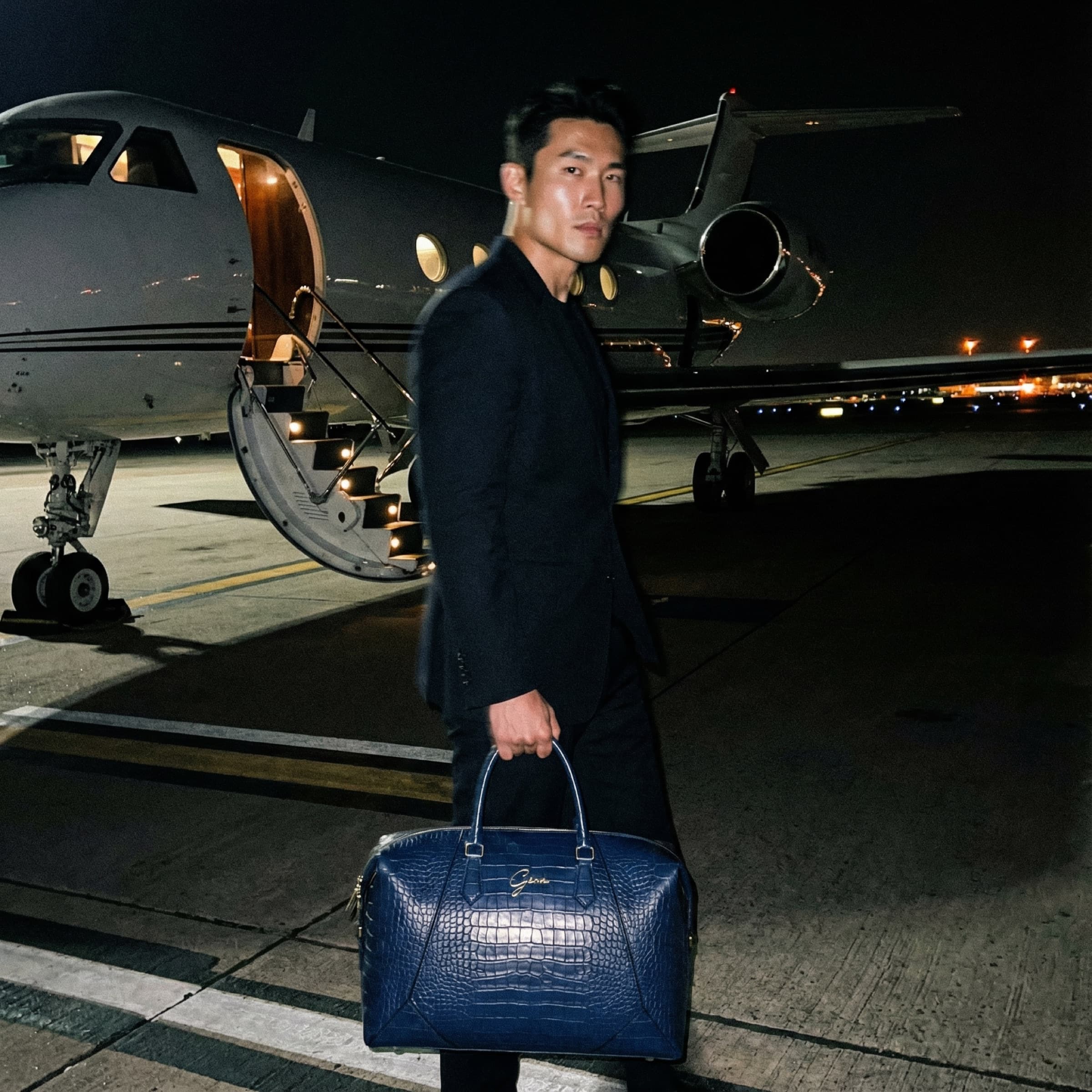 GENA sling bag carried across a private-jet tarmac at night